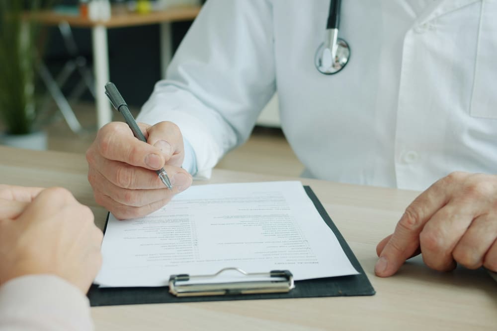 Médico ortopedista anotando o plano de tratamento do joelho durante a consulta